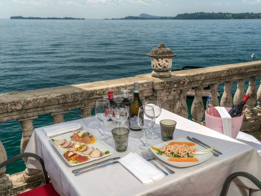 Restaurant Tisch mit Vorspeisen und Wein auf einer Terrasse am See