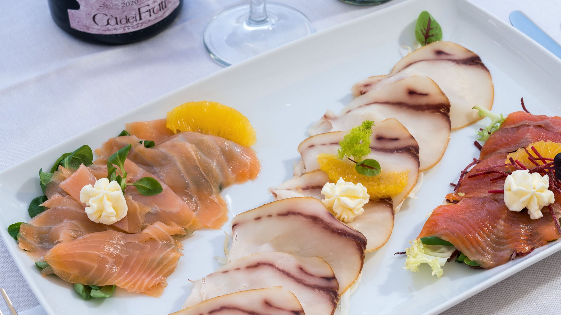 Restaurant Drei Sorten dünn geschnittener geräucherter Fisch mit Garnitur auf weißem Teller