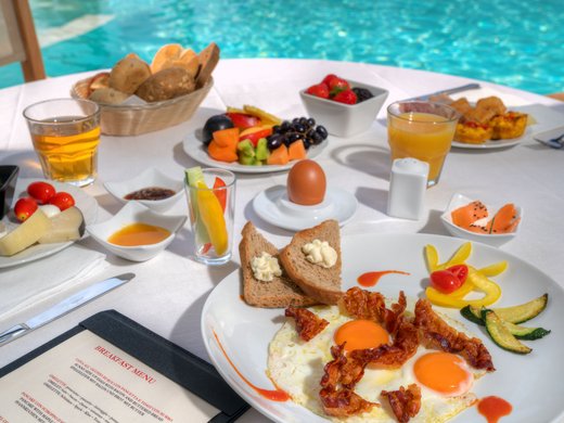 Ein charmantes Bed-and-Breakfast-Konzept in Gardone Riviera Frühstück mit Rührei, Speck, Brot, Früchten und Saft am Pool