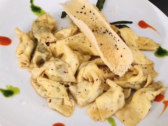 Restaurant Teller mit gewürzter Pasta und Parmesanspäne, garniert mit grüner und roter Sauce