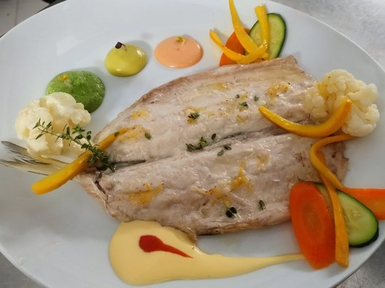 Restaurant Gegrilltes Fischfilet mit Gemüse und drei Saucen auf weißem Teller