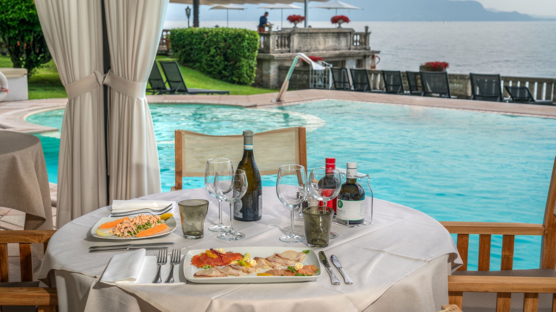 Restaurant Elegantes Tischgedeck mit Speisen und Wein am Pool mit Seeblick