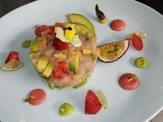Restaurant Feines Gericht mit Avocado, passierter Limette, Erdbeeren und Passionsfrucht auf weißem Teller