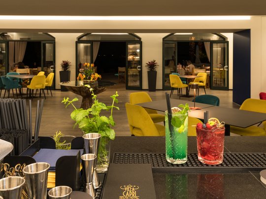 Lässiger Urlaub am Gardasee im 4-Sterne-Hotel Bar mit bunten Stühlen und zwei Cocktails in einem modernen Restaurant
